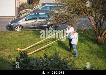 Un Senior est donné une visite d'anniversaire sous la forme d'un duet Alphorn alors qu'elle écoute du balcon d'un immeuble d'appartements à Flums. Banque D'Images