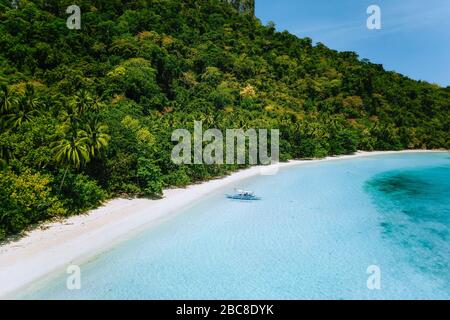 Vue aérienne de bateau amarré au tropical paisible plage de sable blanc avec des eaux peu profondes du lagon de l'océan turquoise et des cocotiers. Billet conce exotiques Banque D'Images