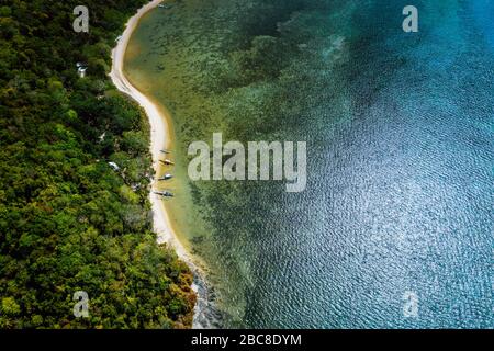 Palawan, Philippines, El Nido. Drone aérien vue ci-dessus d'une plage tropicale déserte isolée avec des embarcations traditionnelles sur littoral en face de rai Banque D'Images