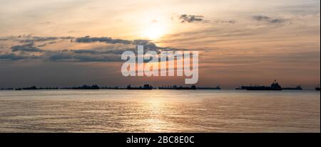 Les navires de fret, les pétroliers et les vraquiers sont ancrés au large du Singapore Straight, à Singapour, au coucher du soleil Banque D'Images