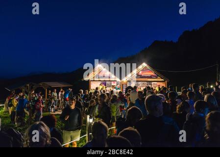 Les visiteurs se tiennent en ligne devant deux stands illuminés d'en-cas pendant le feu du milieu de l'été, Kampenwand, Chiemgau, Bavière, Allemagne, Europe Banque D'Images