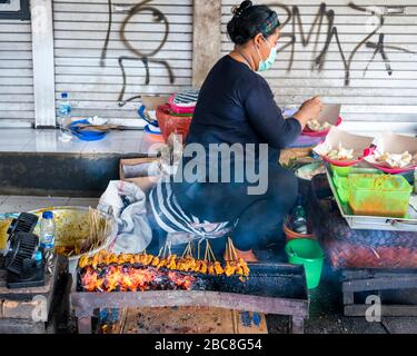 Vue horizontale d'une dame cuisine mangé sur le côté de la route à Bali. Banque D'Images