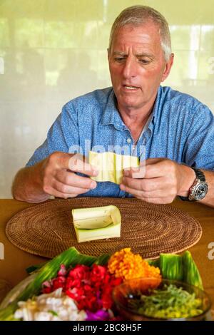 Portrait vertical d'un touriste faisant Canang Sari utilisé dans les bénédictions à Bali, Indonésie. Banque D'Images