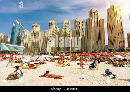 Dubaï, Emirats Arabes Unis 10.31.2018 : plage de JBR Jumeirah bondée avec des touristes profitant du soleil et de la mer avec des gratte-ciel en arrière-plan . Banque D'Images