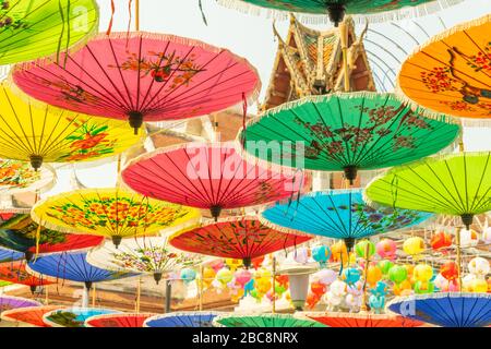 Parasols asiatiques colorés suspendus dans la rue de Bangkok en arrière-plan du toit du temple pendant la journée ensoleillée et chaude Banque D'Images