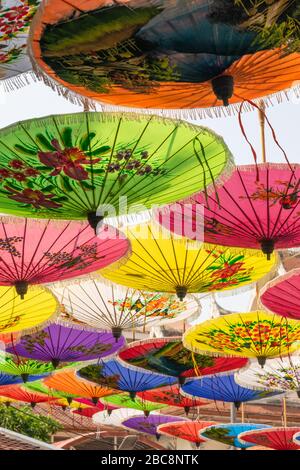 Parasols asiatiques colorés suspendus dans la rue de Bangkok en arrière-plan du toit du temple pendant la journée ensoleillée et chaude Banque D'Images