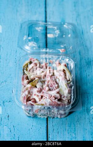 Retirez la salade italienne appétissante avec de la mayonnaise, du jambon et du picker dans un conteneur en plastique. Plat traditionnel. Banque D'Images