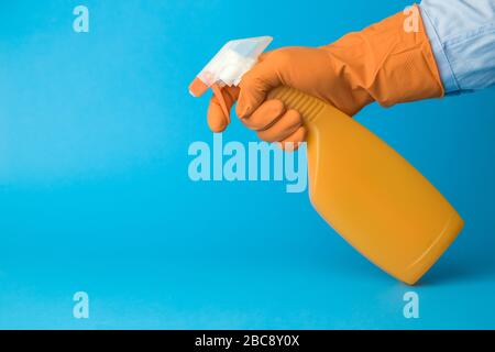 Gants à porter à la main contenant une bouteille de désinfectant sur fond bleu concept créatif minimal. Espace de copie. Banque D'Images