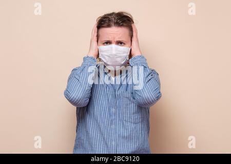 Fille dans le masque médical tenant les mains sur la tête, triste en raison de la maladie se sentant stressée en raison de la pandémie de covid 2019. La femme ne veut pas écouter Banque D'Images