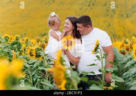 bonne famille s'amuser dans le domaine des tournesols. Père tenant sa fille. Mère tenant le tournesol. Tir extérieur. Banque D'Images