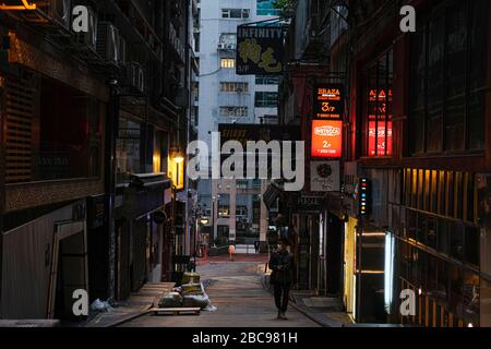 Un homme marche sur une rue vide dans LAN Kwai Fong.le gouvernement de Hong Kong a ordonné un arrêt de deux semaines de pubs et de bars pour resserrer les règles de distanciation sociale. Banque D'Images