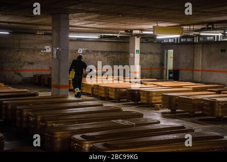 Un homme est en train de désinfecter la zone de stationnement de la mortuaire de Collserola pleine de cercueils, dont la plupart ont le cadavre et d'autres attendent que ceux qui meurent dans les prochains jours.Espagne? Jusqu'à présent, le ministère de la Santé a enregistré 112 065 infections, 10 348 décès et 26 743 cas de récupération depuis le début de l'éclosion du virus corona. Banque D'Images