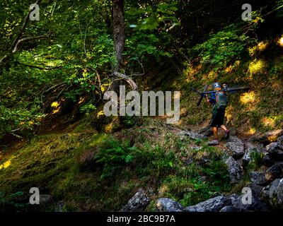 Mountain Biker porte son vélo à la Cascade de Faillitoux. Monts du Cantal, Massif Central, Cantal France Banque D'Images