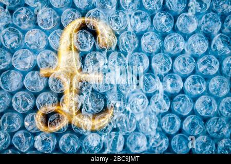 Symbole de la livre britannique dorée fragile protégé sous une couche de papier à bulles en plastique Banque D'Images