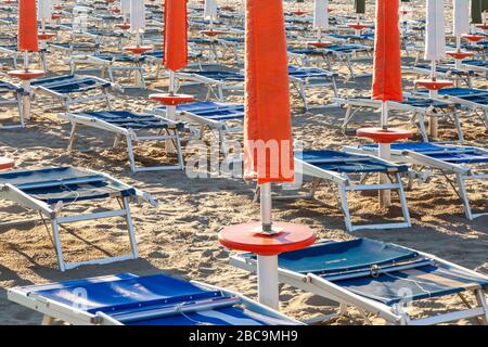 Chaises longues et parasols fermés sur une plage Adriatique, Marina di Ravenna, Emilie Romagne Banque D'Images