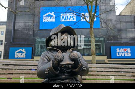 Londres. ROYAUME-UNI. 3 avril 2020. Une statue de bronze de l'ours de Paddington est assise seule sur un banc de Leicester Square, avec des messages pour le NHS sur les écrans du cinéma Odéon pendant le Global Pandemic Credit: Thomas Bowles/Alay Live News Banque D'Images