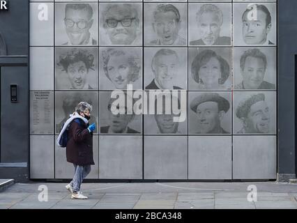 Londres. ROYAUME-UNI. 3 avril 2020. Une dame dans un masque passe devant le mur de renommée du Palladium de Londres alors que le gouvernement demande aux gens de rester à la maison pendant le Coronavirus Global Pandemic Credit: Thomas Bowles/Alay Live News Banque D'Images