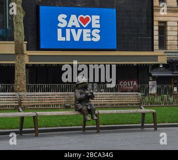 Londres. ROYAUME-UNI. 3 avril 2020. Une statue de bronze de l'ours de Paddington est assise seule sur un banc de Leicester Square, avec des messages pour le NHS sur les écrans du cinéma Odéon pendant le Global Pandemic Credit: Thomas Bowles/Alay Live News Banque D'Images