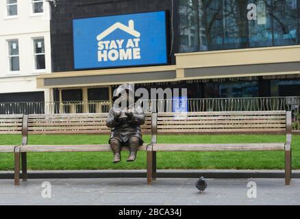 Londres. ROYAUME-UNI. 3 avril 2020. Une statue de bronze de l'ours de Paddington est assise seule sur un banc de Leicester Square, avec des messages pour le NHS sur les écrans du cinéma Odéon pendant le Global Pandemic Credit: Thomas Bowles/Alay Live News Banque D'Images