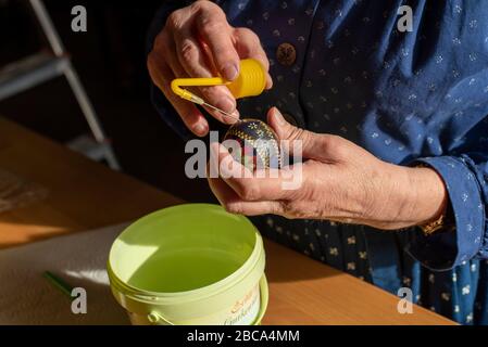 Oeufs de Pâques sorabe, technique de batik de cire, neuvième étape: L'oeuf de poulet décoré est soigneusement soufflé avec un dispositif spécial. Banque D'Images