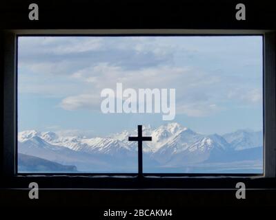 En regardant par la fenêtre de l'Église du bon berger sur le lac Tekapo jusqu'aux Alpes du Sud avec crucifix en premier plan Banque D'Images