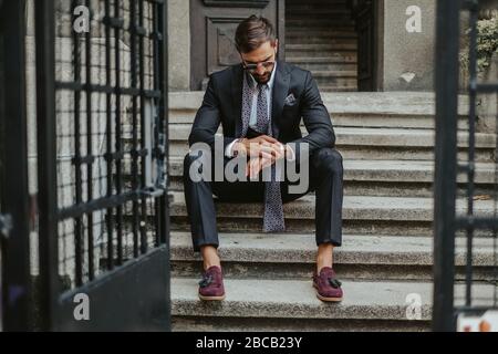 Homme d'affaires nerveux qui attend dans les escaliers en journée et regarde l'heure Banque D'Images