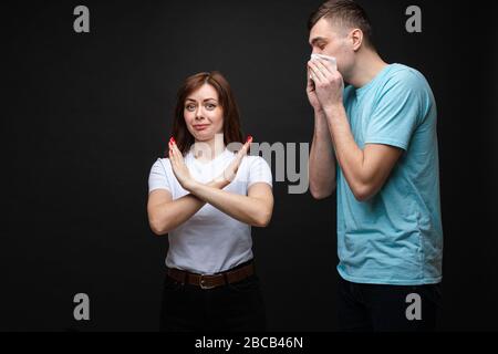 Jeune femme avec un geste d'arrêt et un homme éternuant. Banque D'Images
