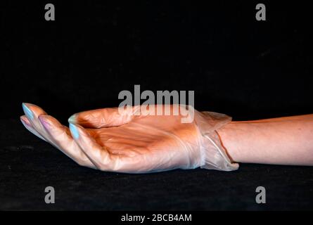 Une main de femme avec une manucure dans un gant en caoutchouc transparent. Banque D'Images