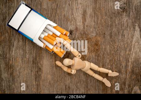 Le mannequin en bois prend une cigarette. Concept de mauvaise habitude. Banque D'Images