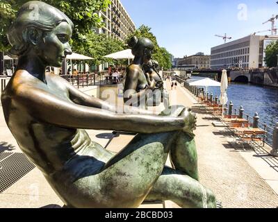 Des figures de bronze de trois filles et d'un garçon assis sur un mur sur un remblai de la Spree à Berlin Banque D'Images