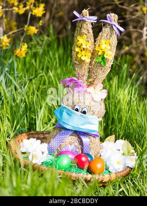 Drôle de lapin de Pâques avec œufs de pâques et masque facial COVID-19 Coronavirus Banque D'Images