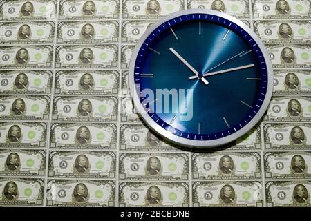 Le concept du temps est l'argent, une horloge murale contre un tas de factures de milliers de dollars. Banque D'Images