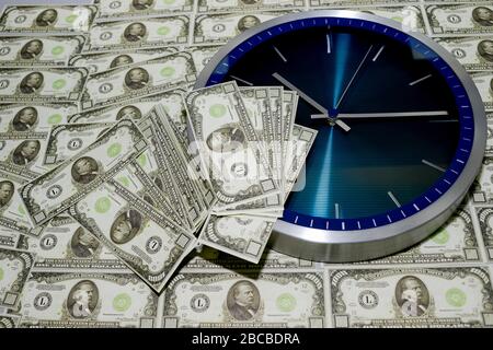 Le concept du temps est l'argent, une horloge murale contre un tas de factures de milliers de dollars. Banque D'Images