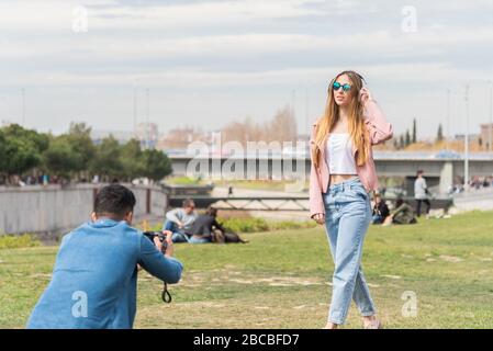 Photographe effectue une photo d'une jeune fille caucasienne à l'extérieur dans un parc urbain Banque D'Images