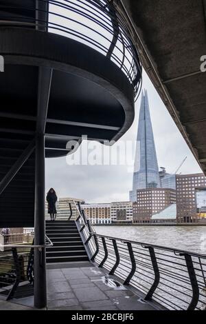 Une femme solitaire située dans les escaliers jusqu'au London Bridge, les escaliers assurent un lien entre le London Bridge et la North Bank Riverside Walkway, Londres, Angleterre, Royaume-Uni Banque D'Images