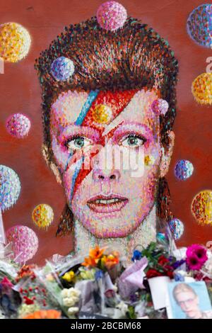 La fresque de David Bowie à Brixton entoure par des offrandes commémoratives posées juste après sa mort, Londres Banque D'Images