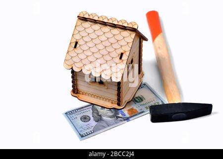 Maison en bois, un billet de 100 dollars et un marteau sur fond blanc, isoler Banque D'Images