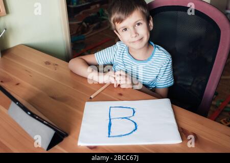 Un enfant heureux affiche la page avec la lettre écrite B, la scolarité à la maison Banque D'Images