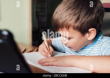 Litle enfant siting au bureau et dessin lettres album avec crayons de couleur, style de vie Banque D'Images