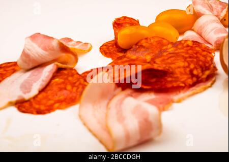 Tranches de bacon, de saucisses et de tomates sur fond blanc. Gros plan Banque D'Images