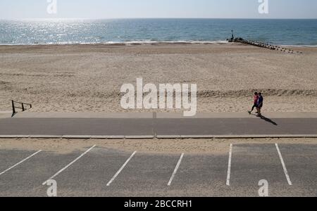 Les gens marchent le long d'une plage déserte de Boscombe, alors que le Royaume-Uni continue de se verrouiller pour aider à freiner la propagation du coronavirus. Banque D'Images