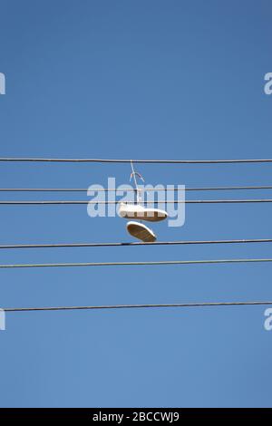 une paire de formateurs jetés sur une ligne électrique, communément cru pour signaler l'emplacement d'un crack maison / tache de trafic de drogue. Peut également être le symbole de Banque D'Images