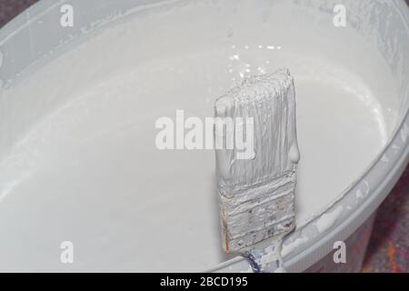 Gros plan de la brosse à peinture et du godet avec peinture murale blanche Banque D'Images