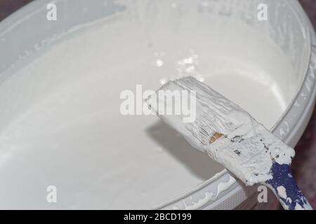 Gros plan de la brosse à peinture et du godet avec peinture murale blanche Banque D'Images