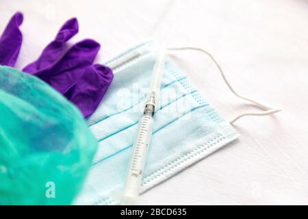 Gants, masque et seringue avec aiguille sur fond blanc. Agents de protection contre les virus, les bactéries. Banque D'Images