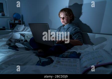 Garçon, à la maison sur l'ordinateur, ordinateur portable, dans la salle des enfants, jouer à un jeu, Banque D'Images