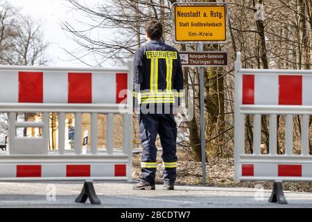 04 avril 2020, Thuringe, Neustadt am Rennsteig: Un pompier se trouve à la barrière de la zone en quarantaine. Depuis presque deux semaines, la place dans la forêt de Thuringe est en quarantaine en raison d'un nombre croissant de personnes souffrant de Covid-19. Photo: Michael Reichel/dpa-Zentralbild/dpa Banque D'Images