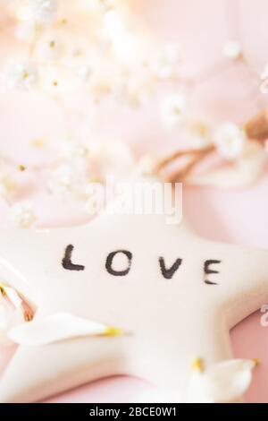 Life Quote - Amour sur une étoile en céramique blanche - image de concept de vie toujours sur un fond rose doux et délicat Banque D'Images