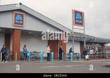 Les gens distancient socialement dans une file d'attente devant le supermarché Aldi pendant le confinement de covid 19 dans le Lincolnshire DE BOSTON, Banque D'Images