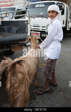 Les enfants et les jeunes hommes vêtus intelligemment travaillant sur le marché du bétail hebdomadaire du vendredi à Nizwa, Oman Banque D'Images